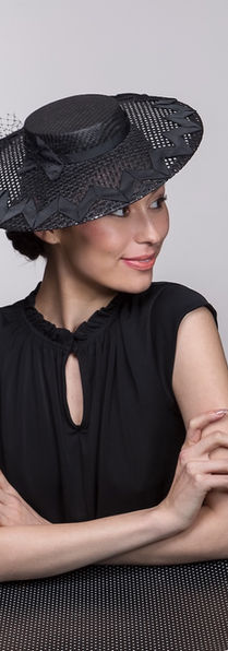 Black boater-style hat by Melbourne milliner Catherine Storm with open woven brim and black trim.