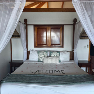 Bed at Hopkins Bay Belize with 'Welcome' message in flower pedals