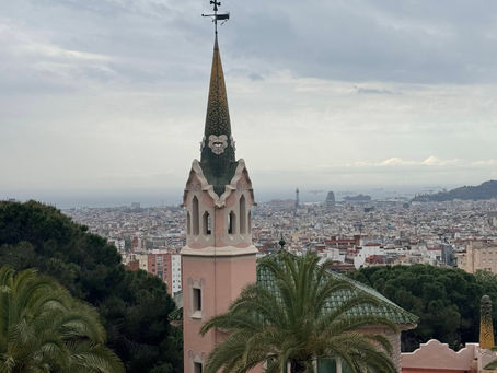 A skinny pink building with a green spire and a cityscape view