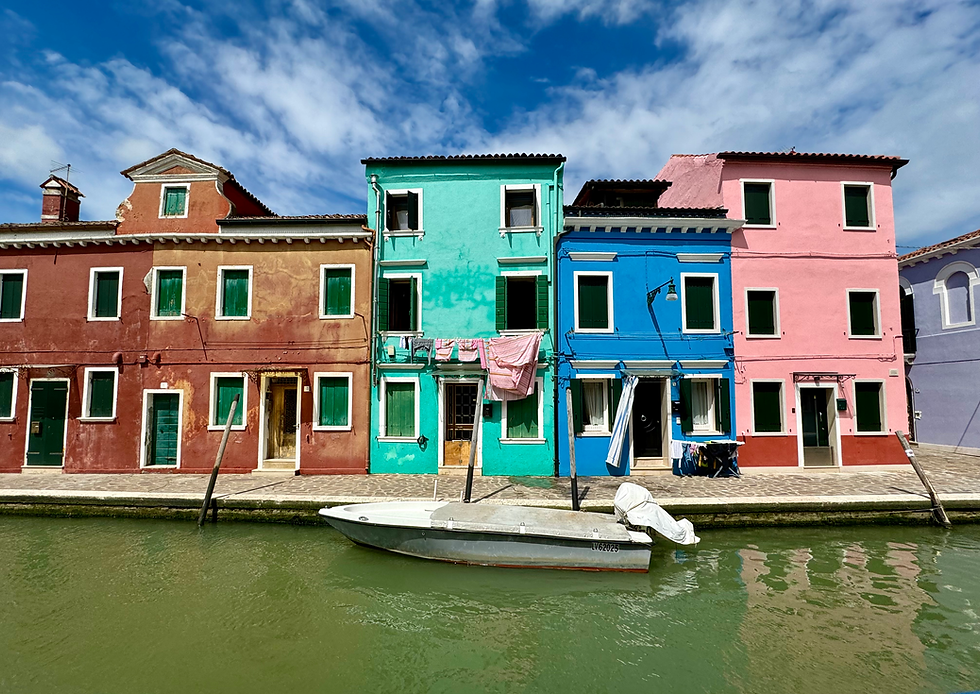 Clothes hang drying infront of a teal house in Burano.