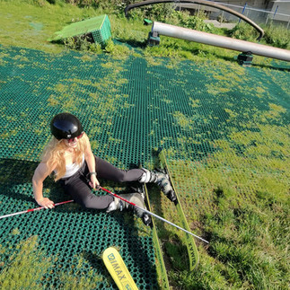 A woman sitting on a hill with skis on