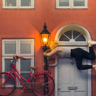 An optical illusion of a woman hanging on a light post