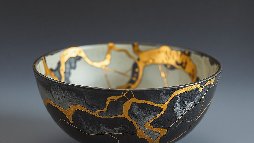 A black bowl with gold cracks sits on a gray surface, showcasing a Kintsugi design. The background is plain, highlighting its elegance.