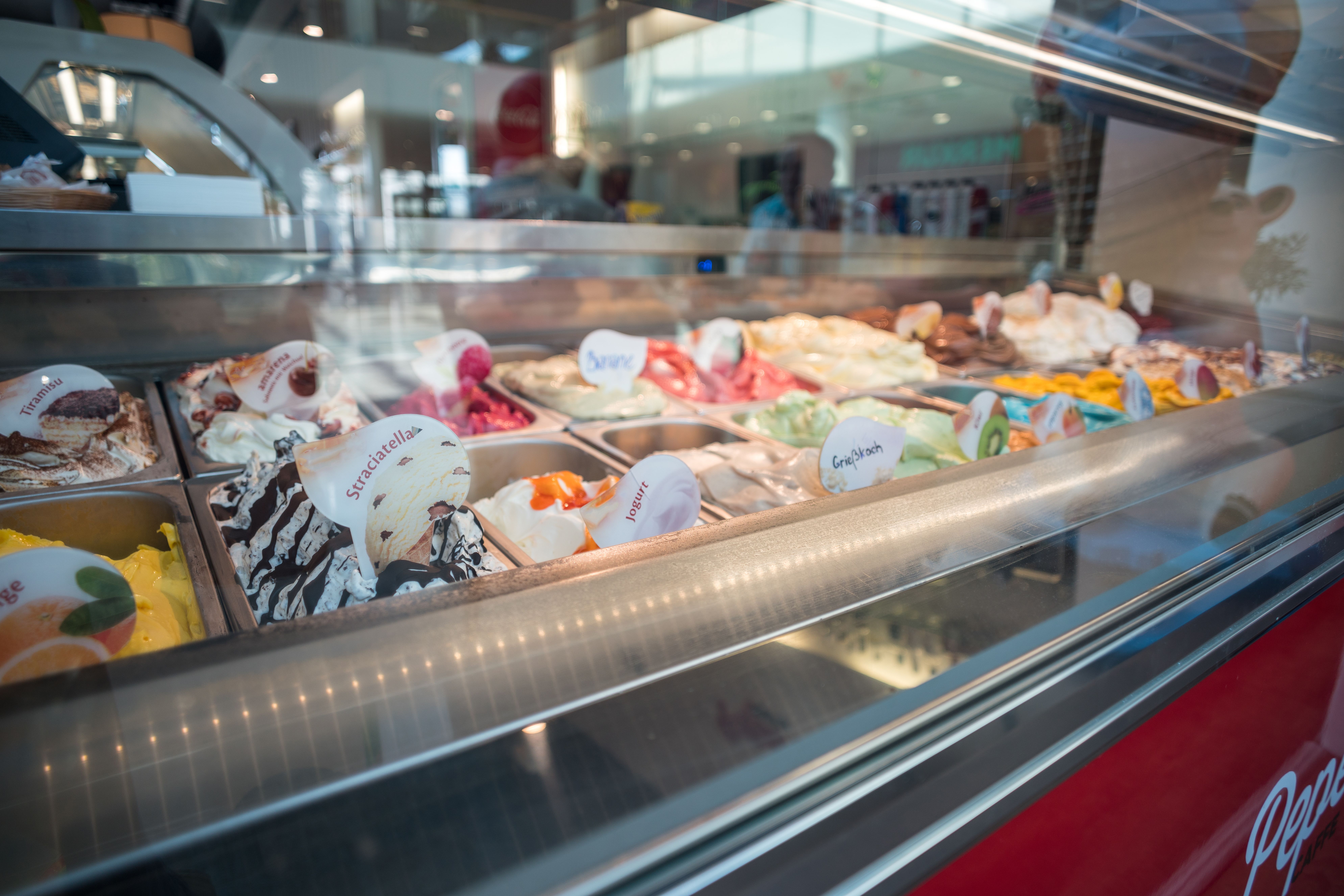 Glass-front commercial gelato freezer displaying frozen desserts