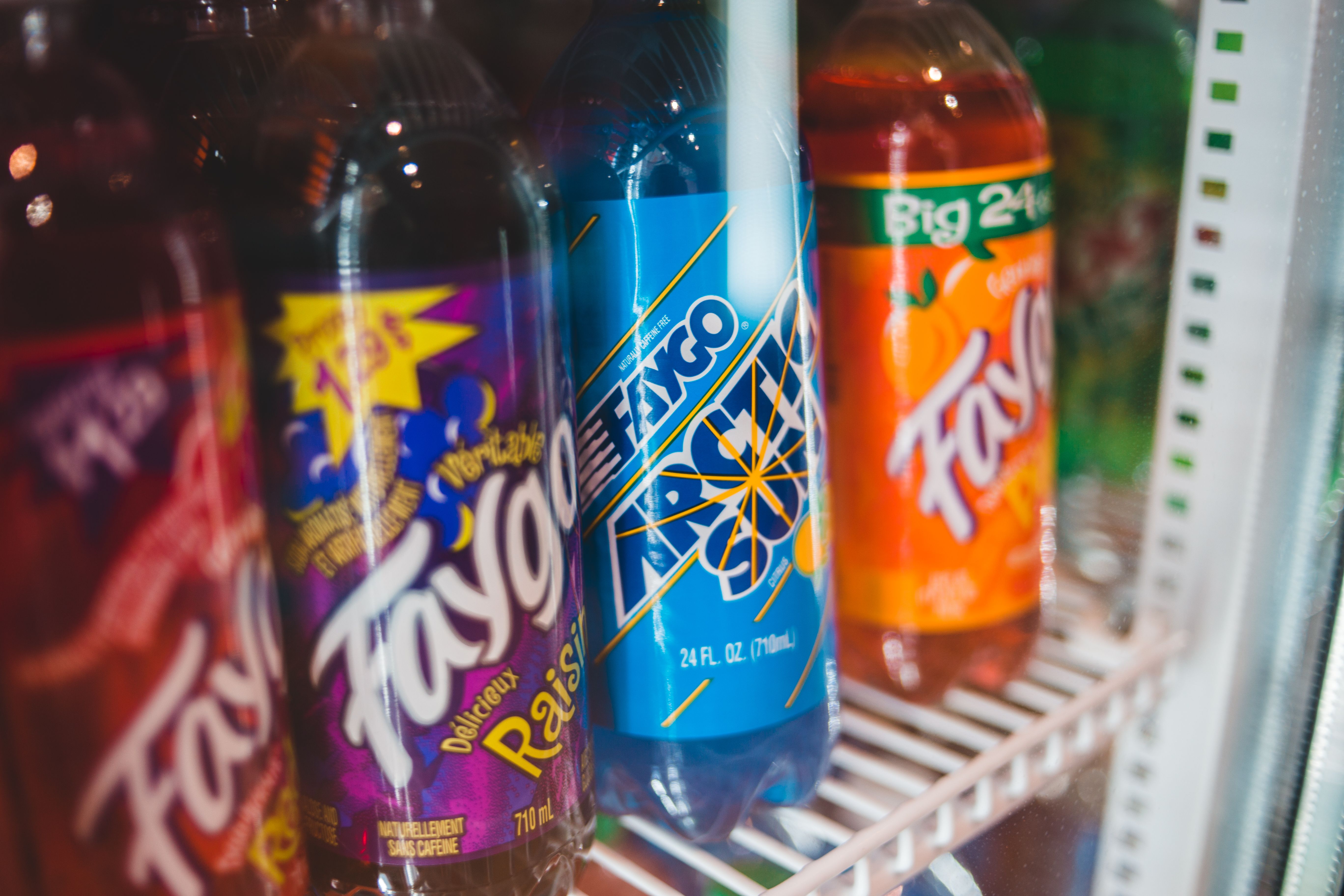 Bottled drinks on a wire shelf inside a refrigerated display case