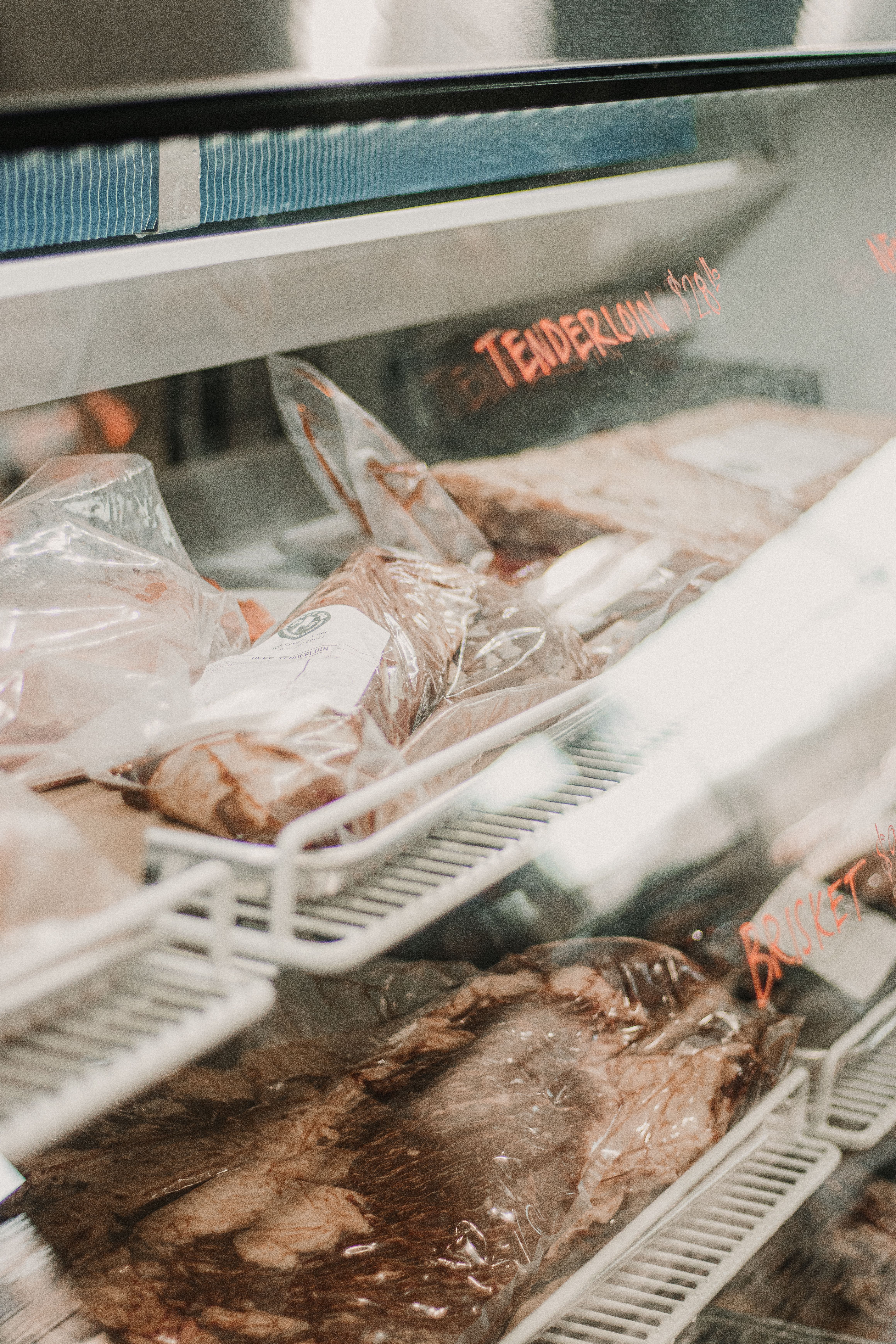 Fresh meat displayed inside a refrigerated butcher counter
