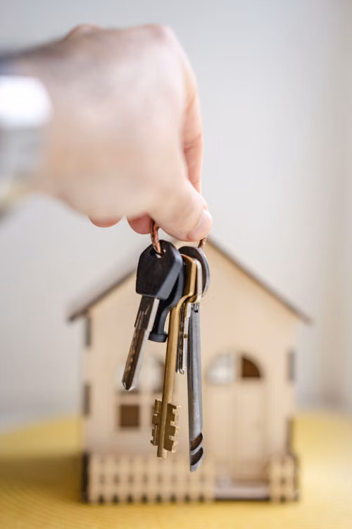 House keys held beside a model home
