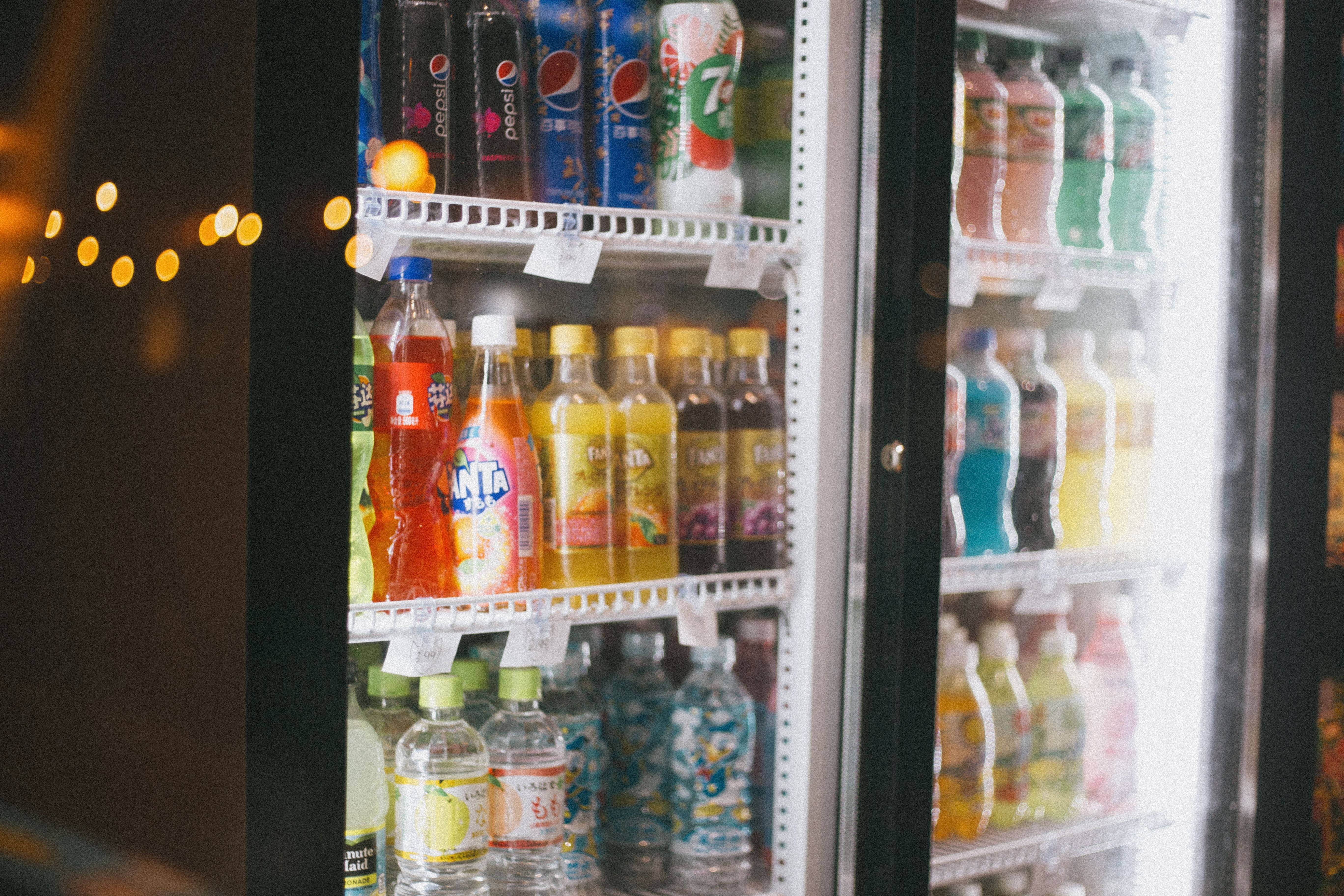 Bottled beverages on shelves inside a glass-door commercial refrigerator