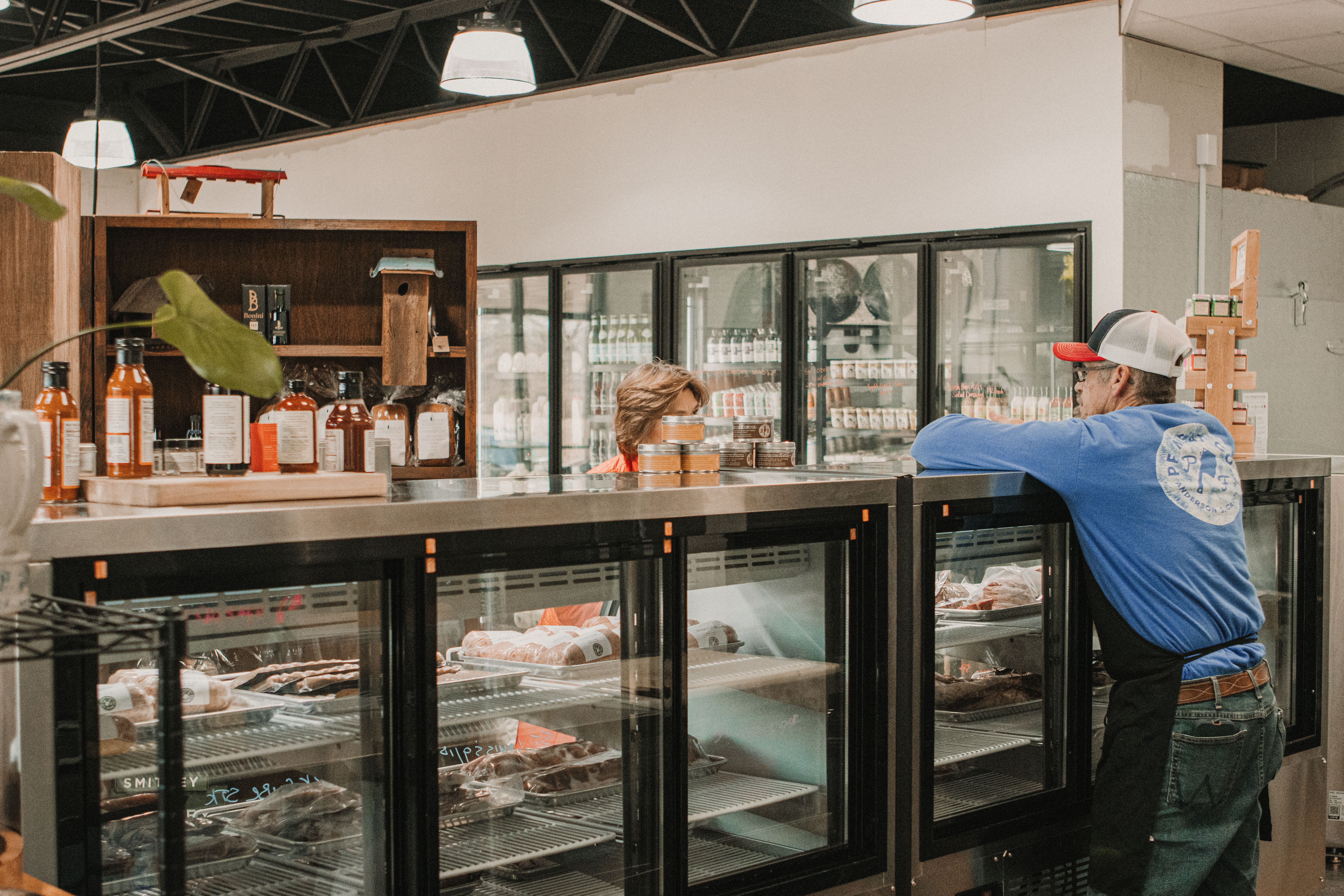 Butcher counter and upright refrigerated cases in a food market