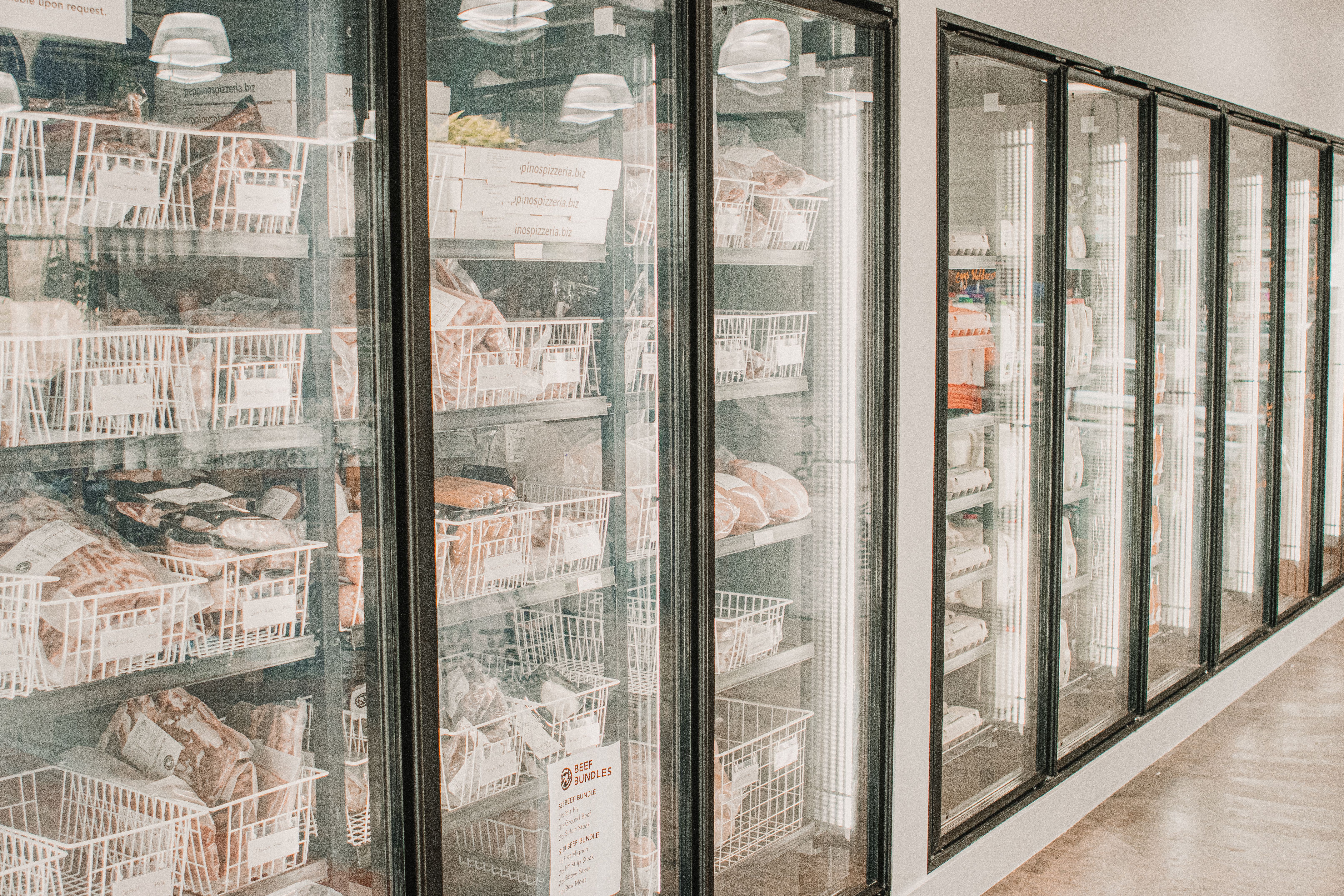 A row of glass-door commercial freezers in a grocery store
