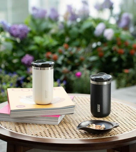 Wacaco Octaroma Lungo in Onyx Black & Ceramic White sitting on table with books.
