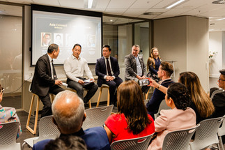 Panel seated at front of room with a large audience seated facing the panel