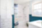 Well-designed hall bathroom remodel with integrated storage cabinetry, soft blue wall paneling, marble-look flooring, and chrome fixtures balanced with softened fixture silhouettes.