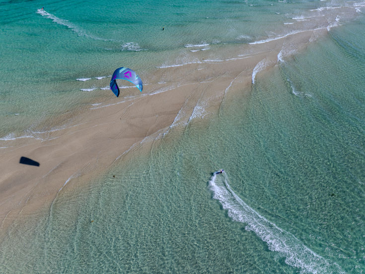 Aerial view of kite surfer on turquoise waters.