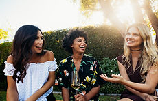 Happy young female friends hanging out and talking at outdoors party Group of young women