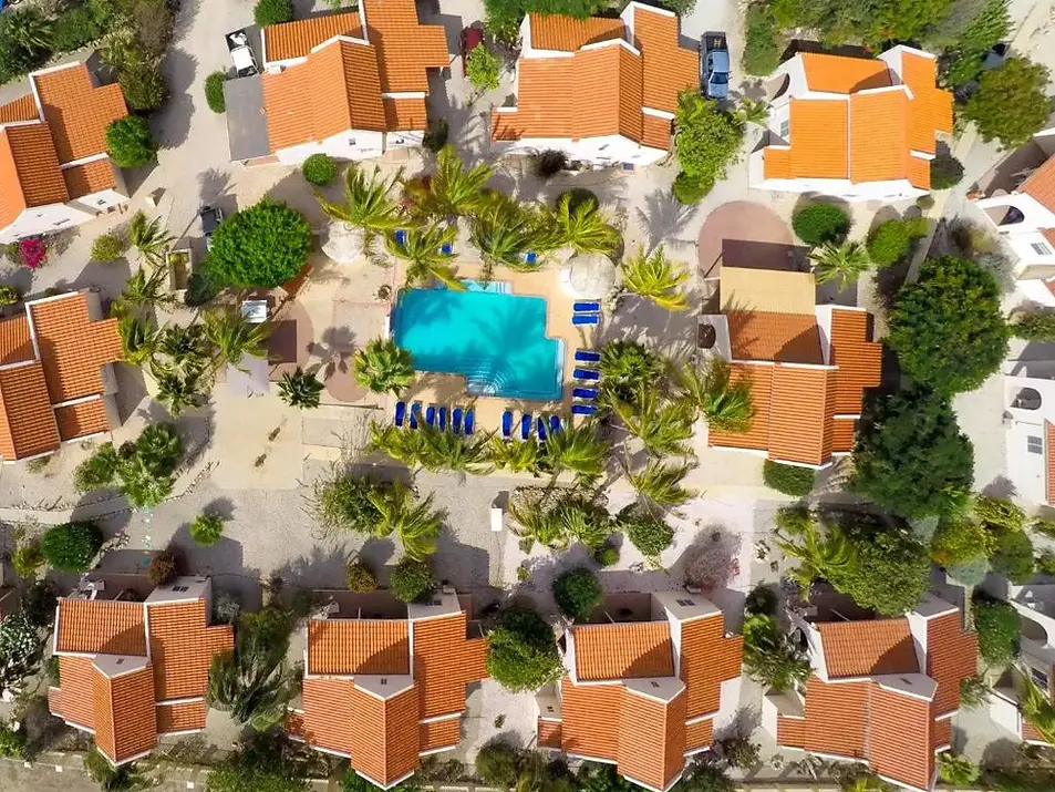 Hamlet Oasis Bonaire luchtfoto van appartementen met oranje daken rond het zwembad, tropische tuin en palmbomen bij dit rustige vakantie resort in Kralendijk.