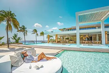 Luxe resort op Bonaire met infinity pool aan zee, moderne architectuur en zonovergoten loungeplek, ultieme tropische vakantiebestemming in het Caribisch gebied.