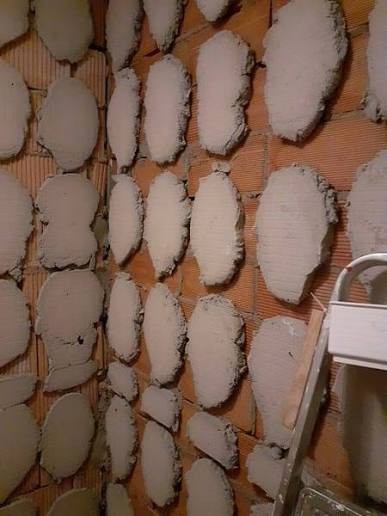 Exposed wall with old mortar blobs after tile removal