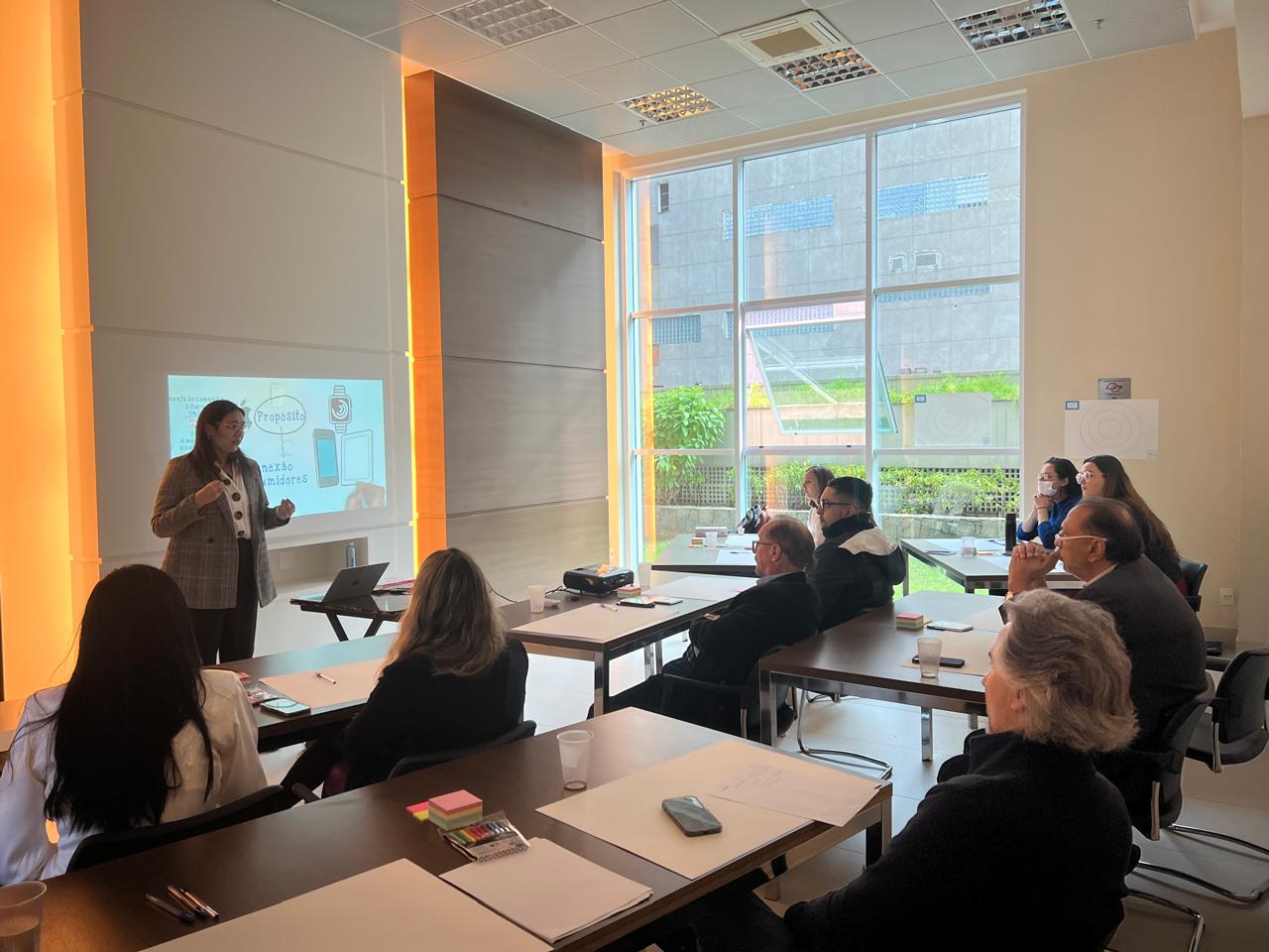 Airyn conduz um workshop presencial com participantes em uma sala iluminada