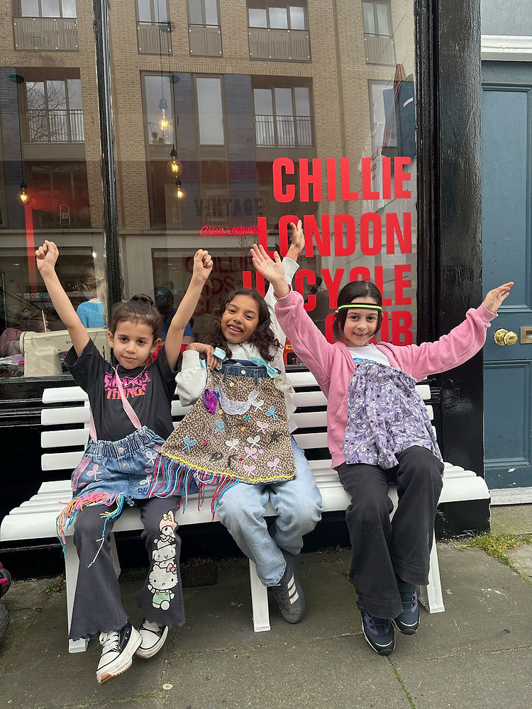 Three children at The Chillie Kids Club birthday party, happily standing together and holding colourful bags they made.