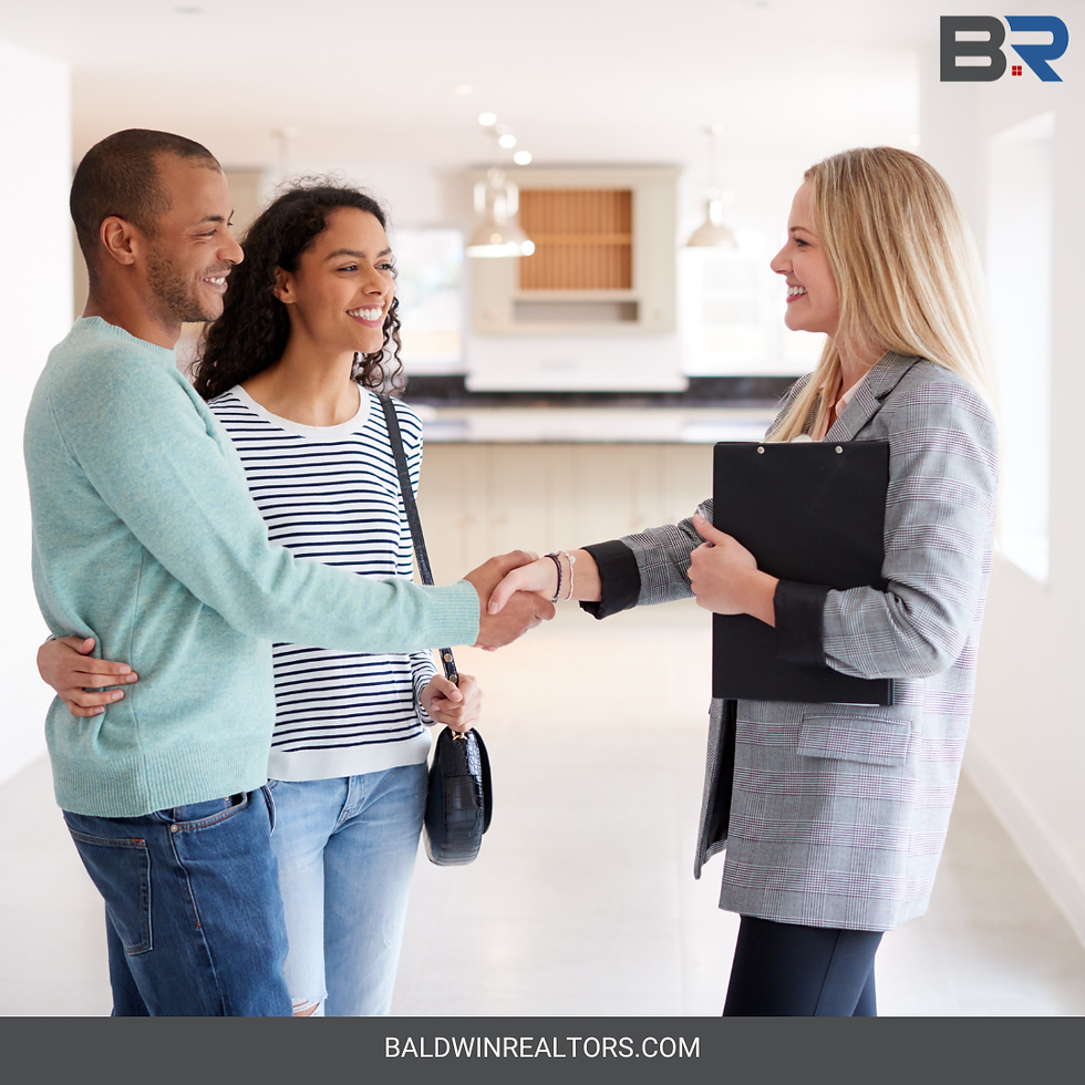 Woman REALTOR shaking hands with man and woman inside home