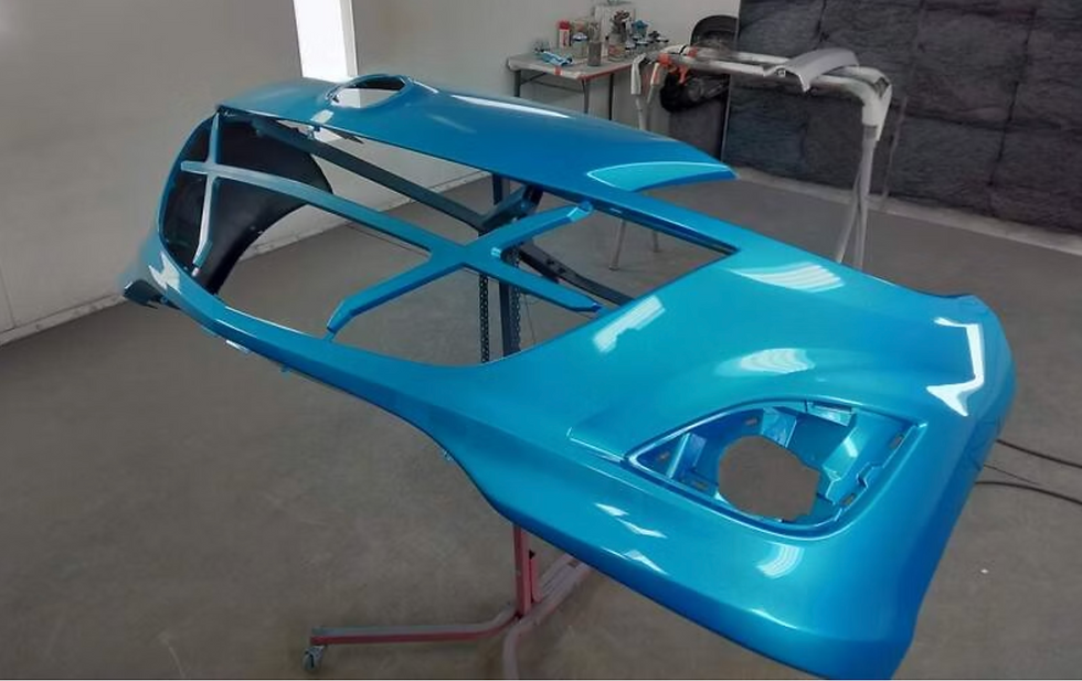 Glossy blue car body shell on a stand in a workshop, with open cutouts and windows, suggesting repair or custom painting