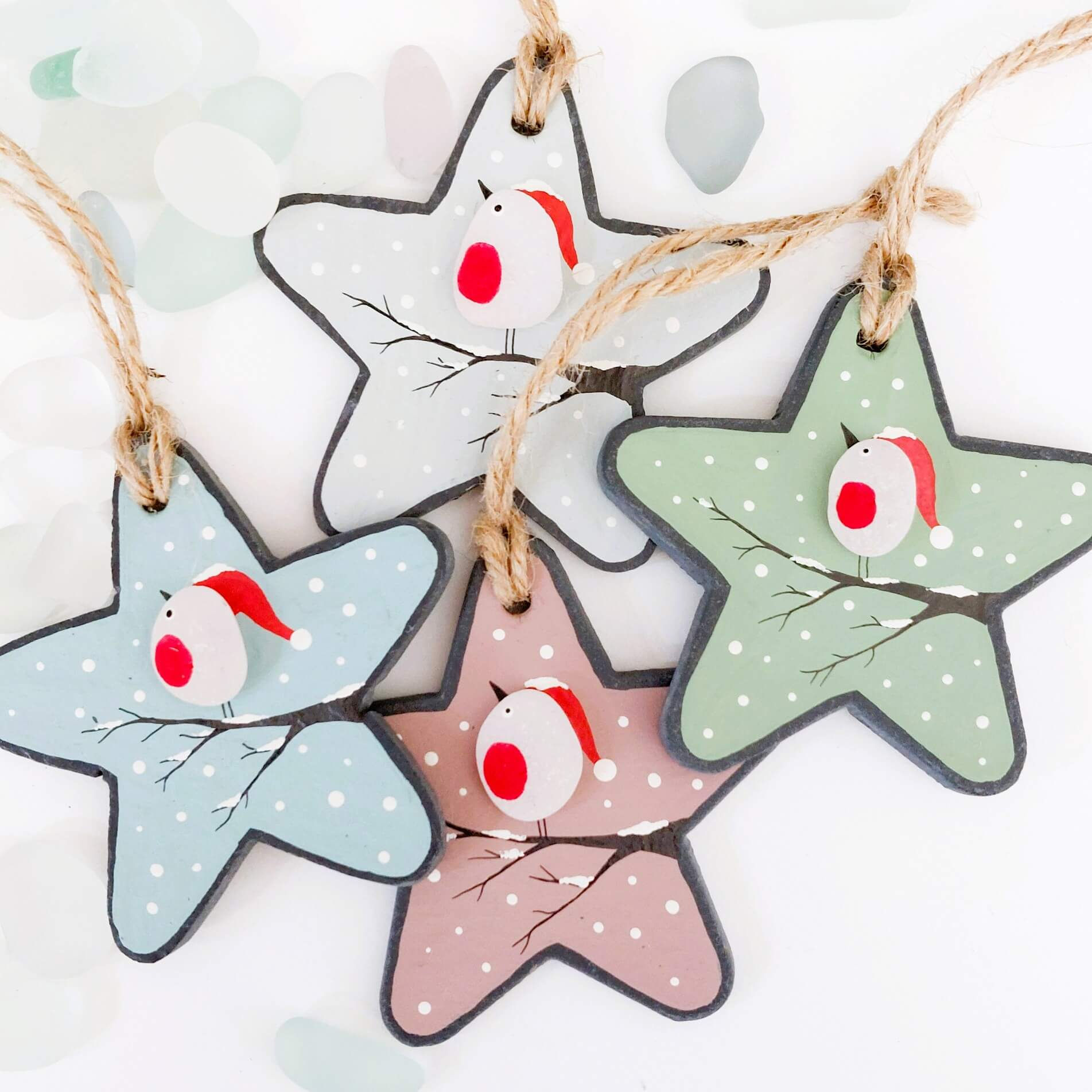 A selection of slate star-shaped Christmas hanging decorations. Individually hand painted and embellished with sea glass