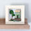 Thumbnail: A square wooden picture, painted white and decorated with reclaimed wood and beach finds showing a green cottage with tree