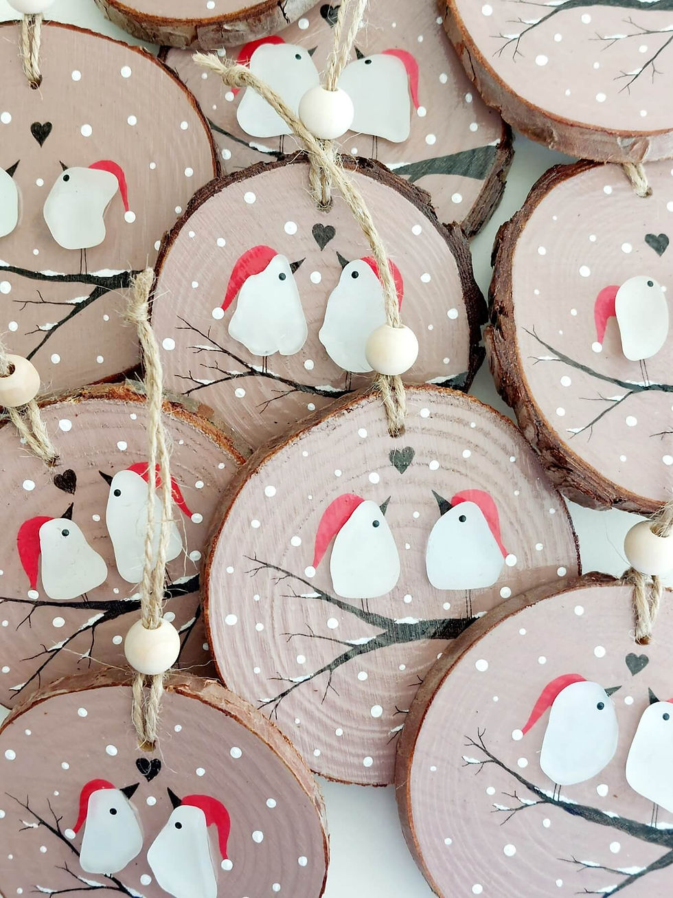 Thumbnail: Wooden log slices, painted pink and decorated with a snowy branch on which is perched 2 birds in santa hats