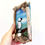Thumbnail: A hand holding a puffin wall art made from driftwood, shells, sea glass and showing a puffin made from painted pebbles