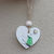 Thumbnail: Green sea glass bird holding a wooden heart on a white hanging heart decoration with jute string and wooden bead.  Copy