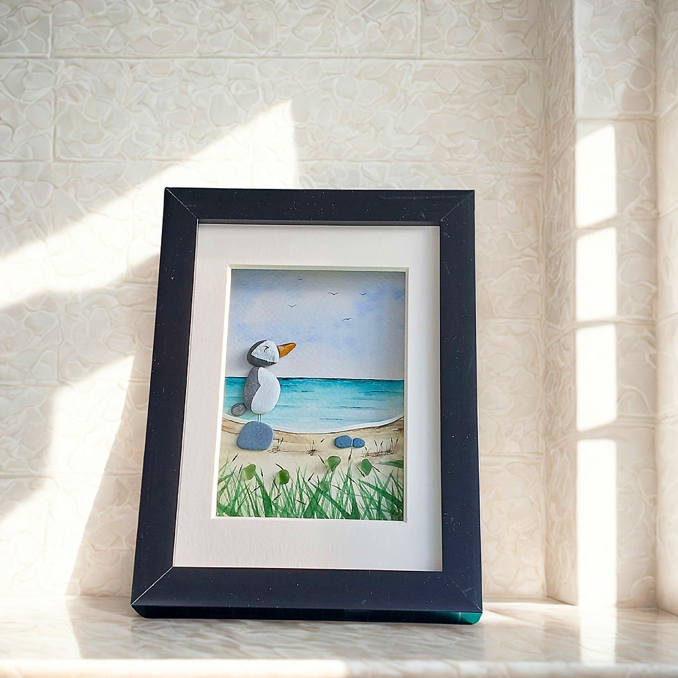 Thumbnail: A black framed 3D watercolour painting of an blue ocean with grasses and sand dunes in the foreground and a pebble puffin.