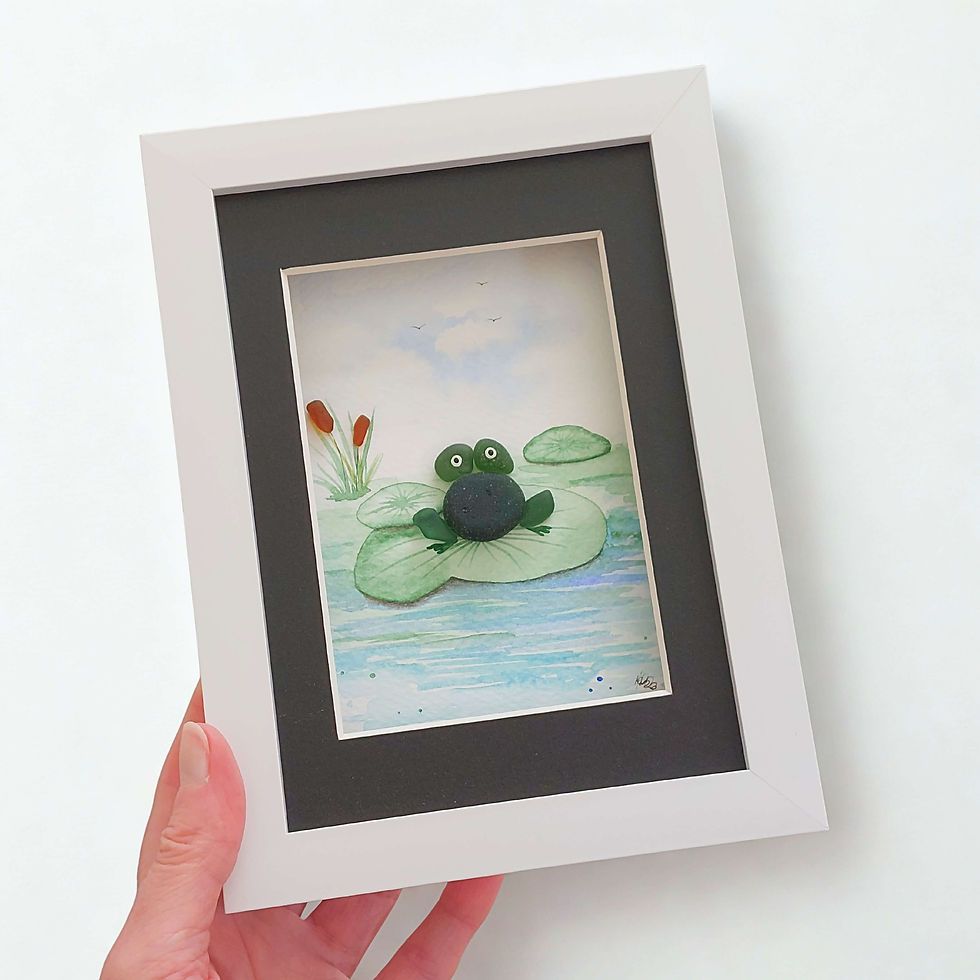 Thumbnail: A white framed 3D watercolour painting of a green frog perched on a lilypad. The frog is made from green sea glass.