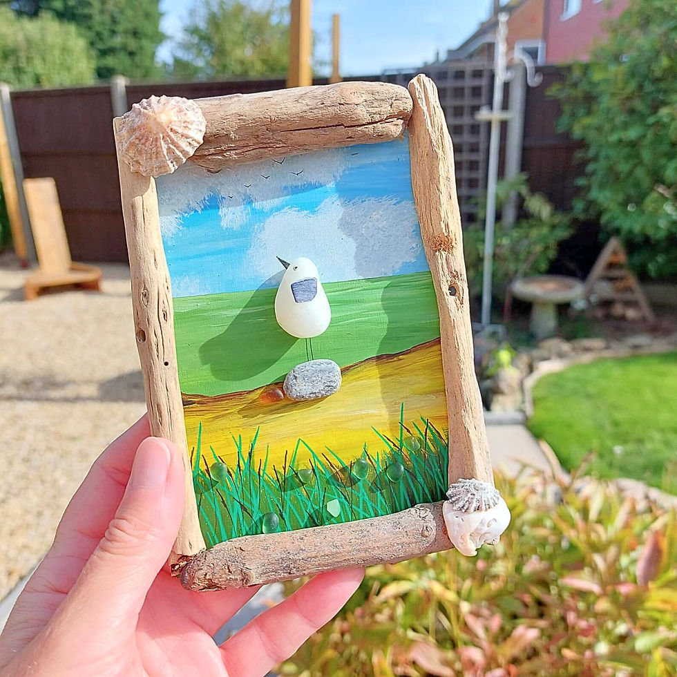 Handmade seagull pebble art featuring a hand-painted bird perched by the sea, framed with natural driftwood