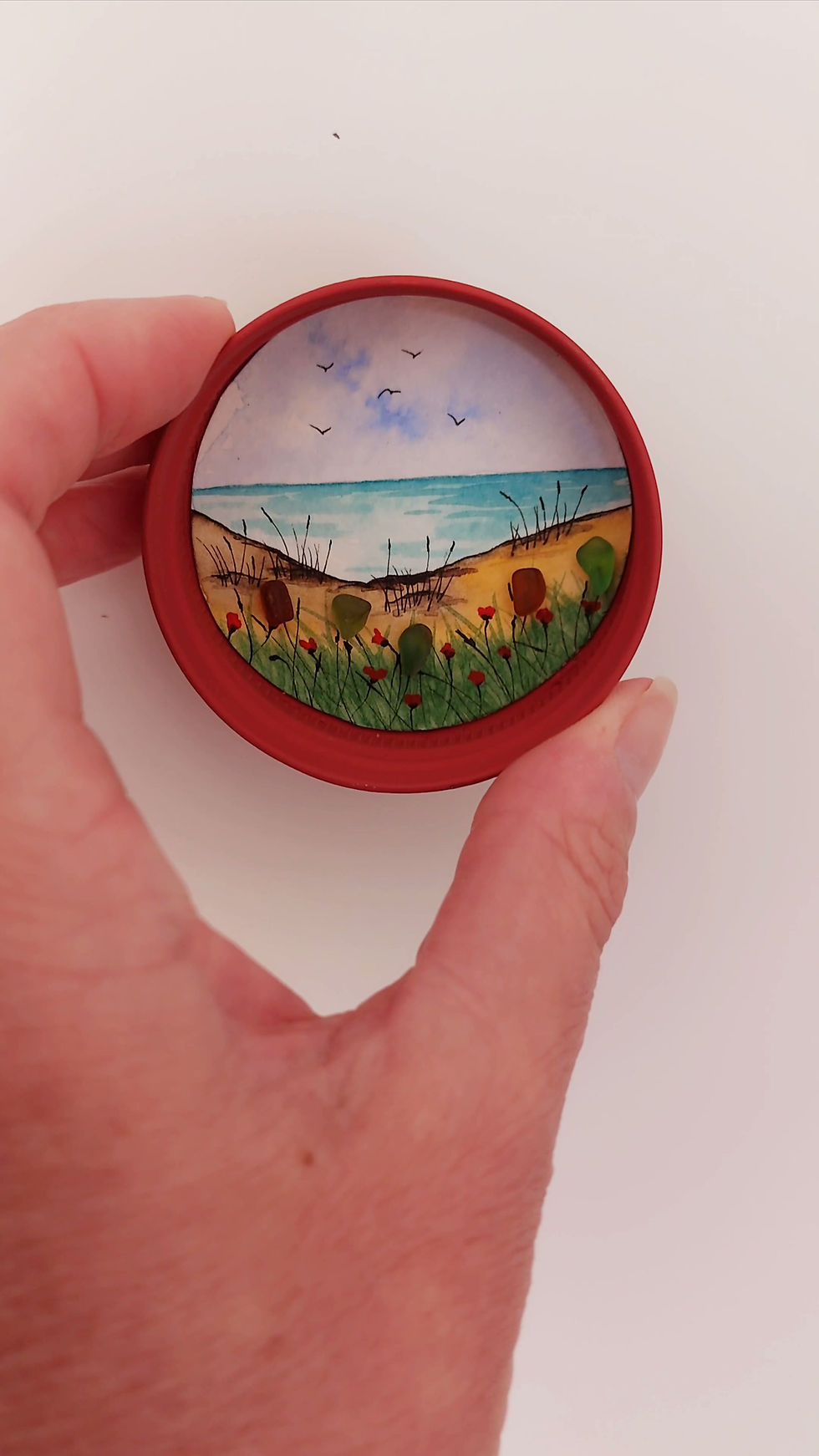 Thumbnail: Handmade coastal fridge magnet with hand-painted beach scene, sea glass flowers and recycled red jar lid.