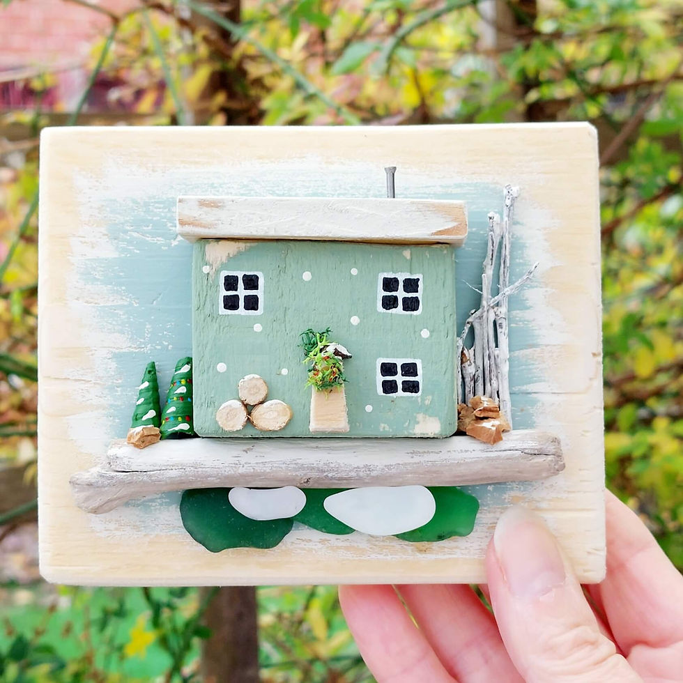 Thumbnail: Rustic wooden wall art, showing a wooden backboard, decorated with a green Christmassy cottage, with driftwood and sea glass