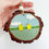 Thumbnail: A hand holding a wooden hanging decoration, hand painted and decorated with sea glass to depict an Easter Chick