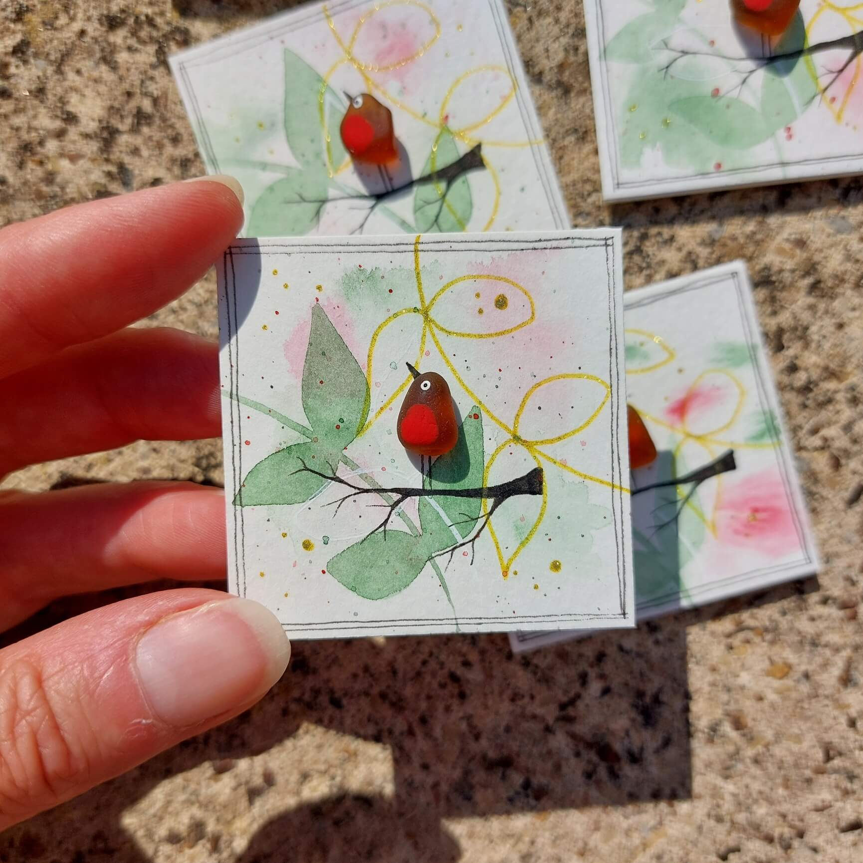 Handmade sea glass robin fridge magnet on a mini watercolour canvas, featuring a robin perched on a branch with delicate bota
