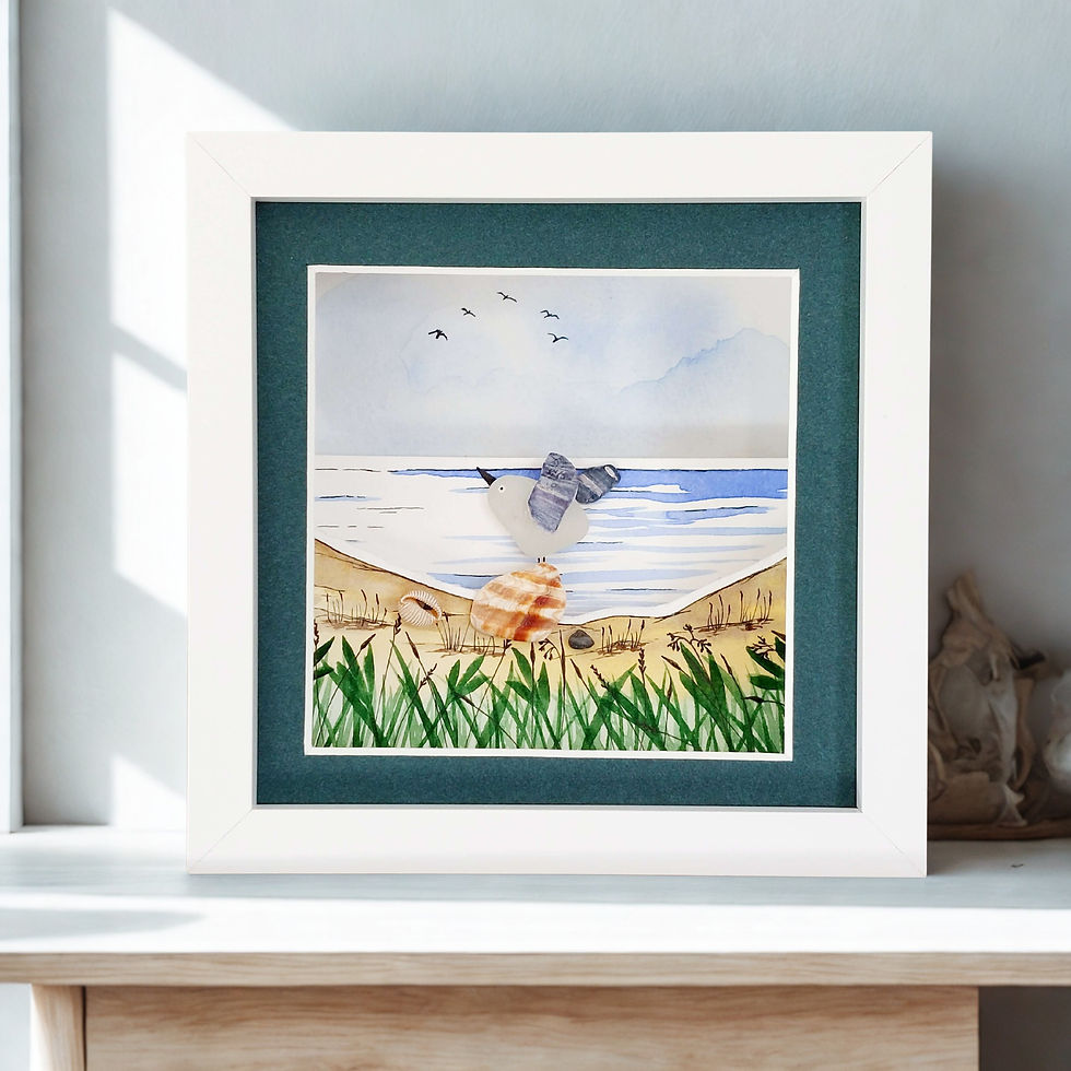 A white framed hand made 3D watercolour picture showing a seagull made from sea glass perched on a shell.
