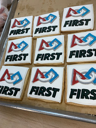 Square cookies with FIRST logo and text. Presented on a baking sheet. Carlyscustomcakes.