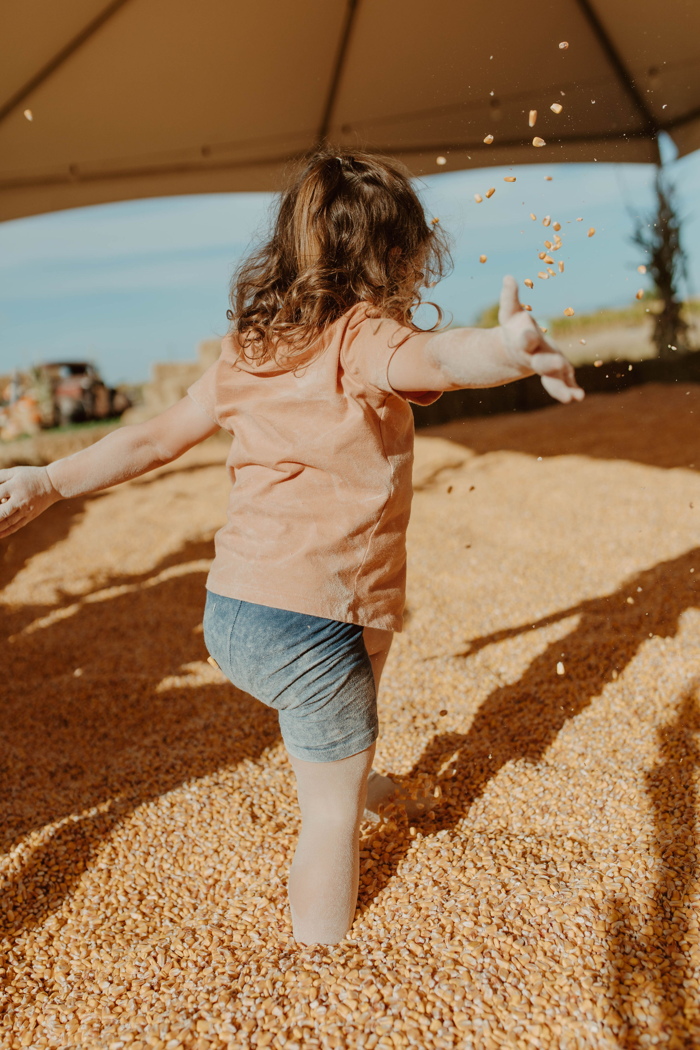 Child playing in a corn-filled activity area at Ten Mile Farms