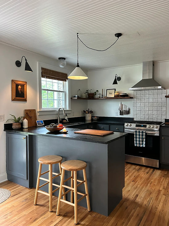 Modern kitchen featuring elegant dark soapstone countertops with a smooth matte finish, paired with white cabinetry and stain