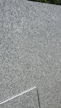 Polished slab of Luna Pearl granite featuring a consistent pattern of light gray, white, and black mineral specks.