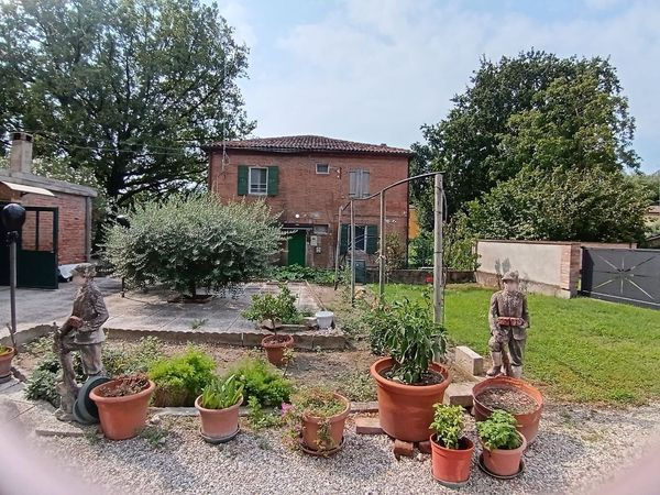 Foto esterna di una casa colonica con giardino e vasi di piante