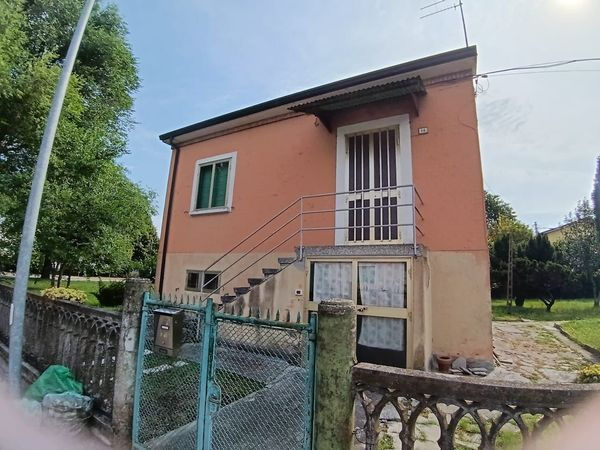 Foto di una casa indipendente a due piani con facciata color pesca, scattata in una giornata di sole, adatta a portfolio immobiliare, formato orizzontale.