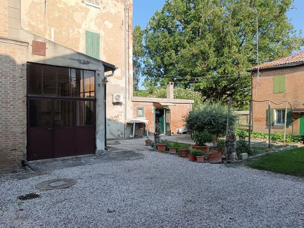Cortile esterno di una casa di campagna con ghiaia e vasi di piante