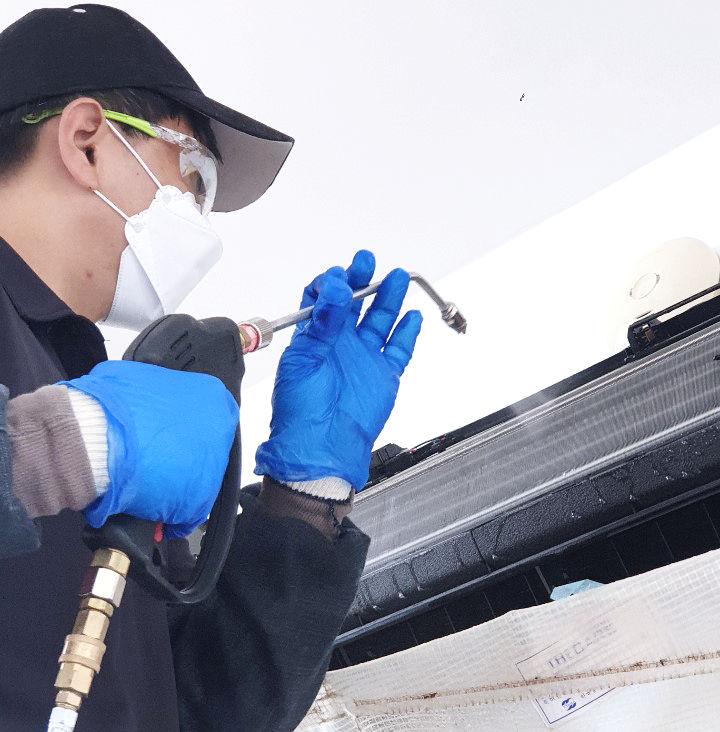 Technician cleaning inside a split system air conditioner