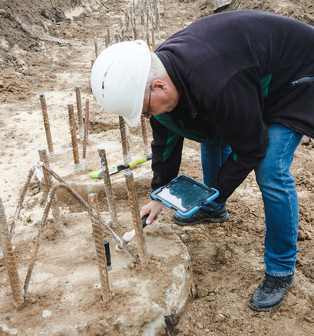 Arbeiter nimmt Bodenproben für Baugrunduntersuchung, Vorbereitung auf Bauprojekt.