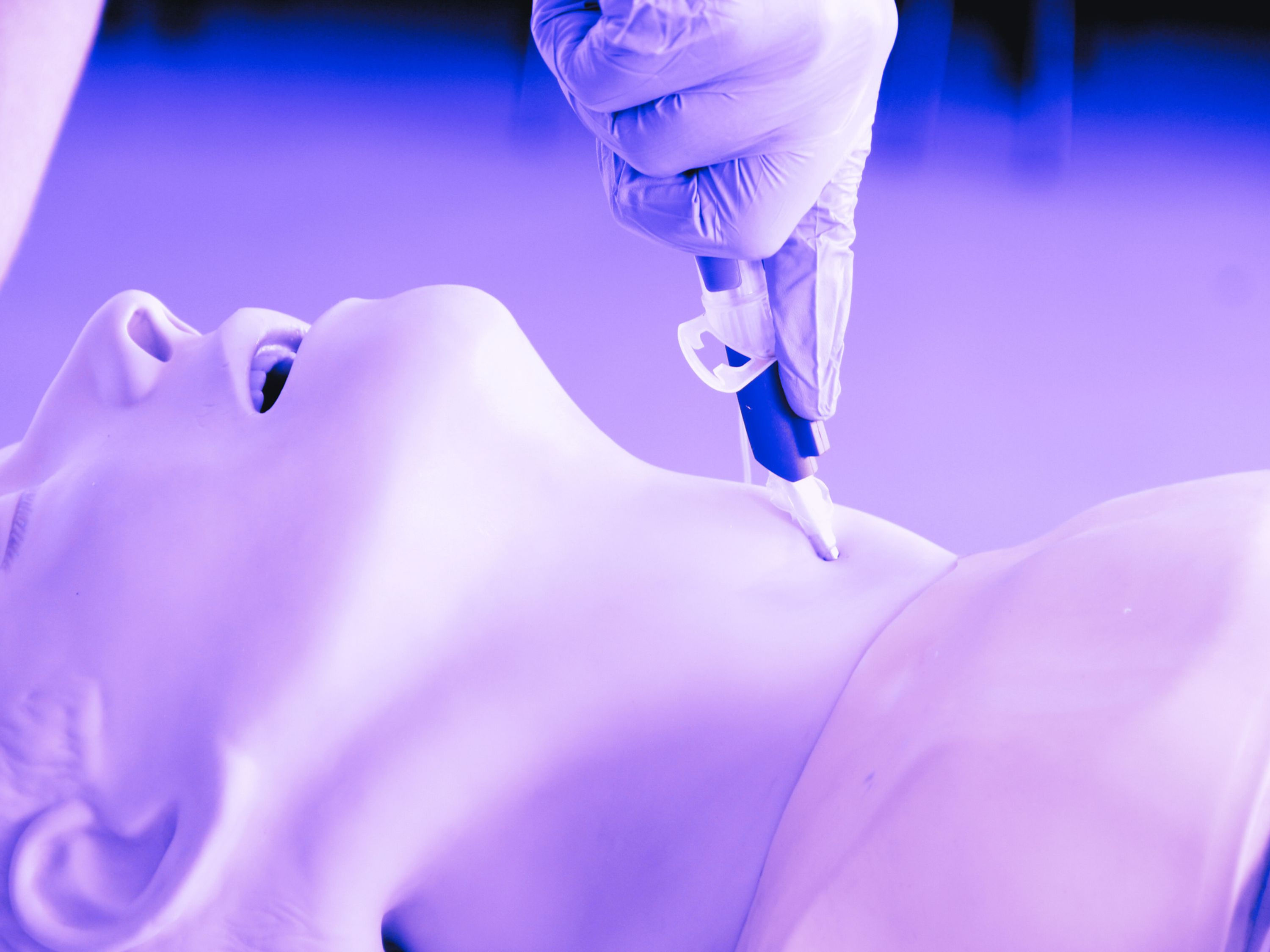 Healthcare professional practising tracheostomy procedure on a simulation manikin during clinical training session.