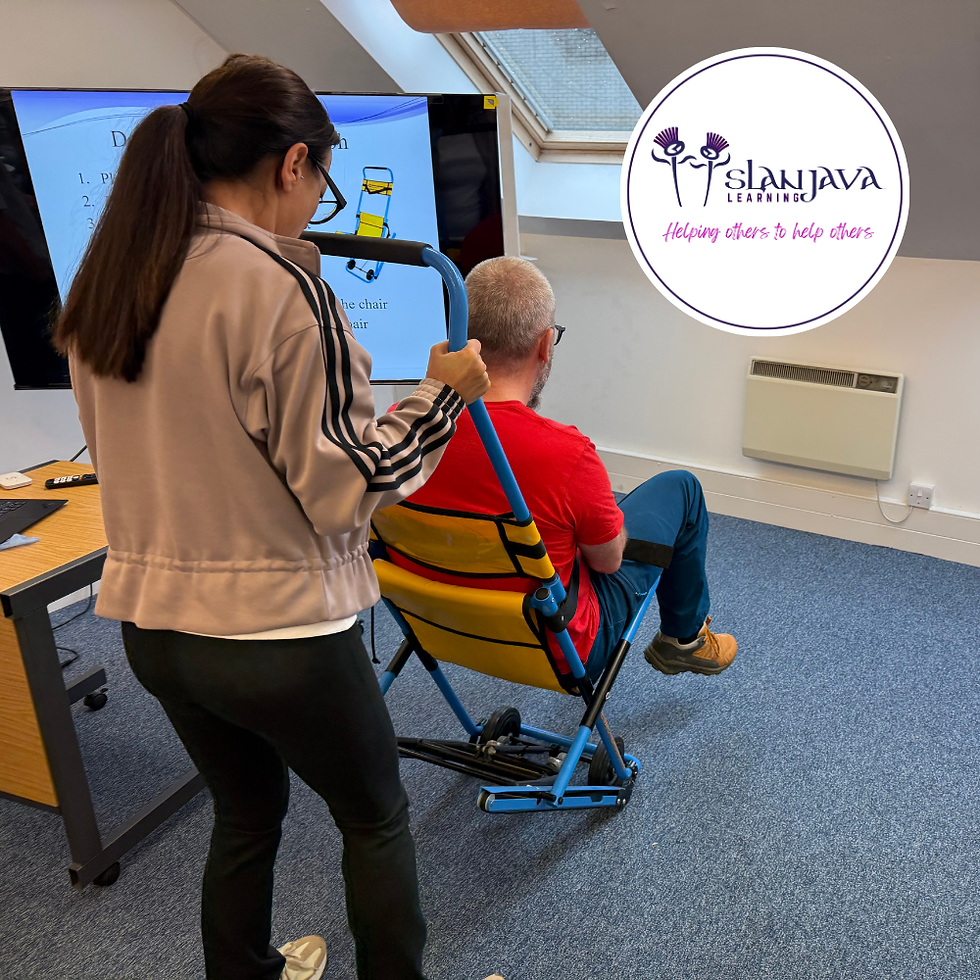 training delegate operates an evacuation chair during a practical session, safely guiding a colleague seated in the chair, with a presentation slide displayed in the background.
